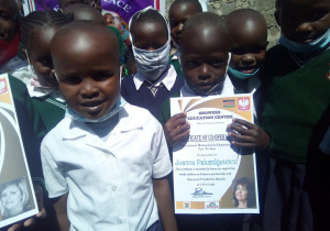 Zdjęcie przedstawia grupę kenińskich dzieci, jeden z chłopców trzyma w reku podziękowania dla nauczyciela za zaangażowanie w akcje.